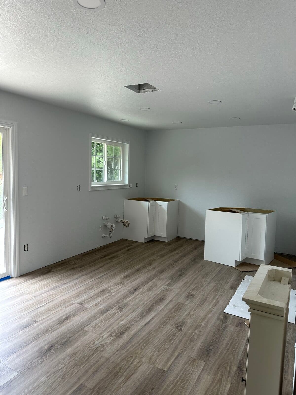 White shaker corner base cabinets set in place on new wood-look vinyl plank flooring