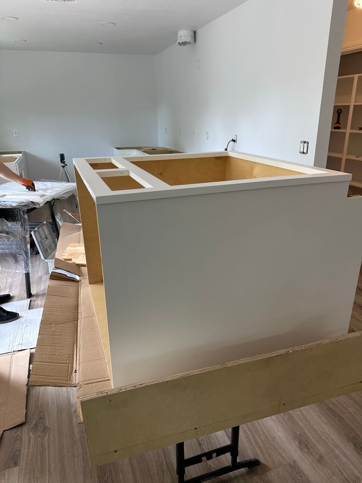 White cabinet box being assembled on sawhorses inside the house