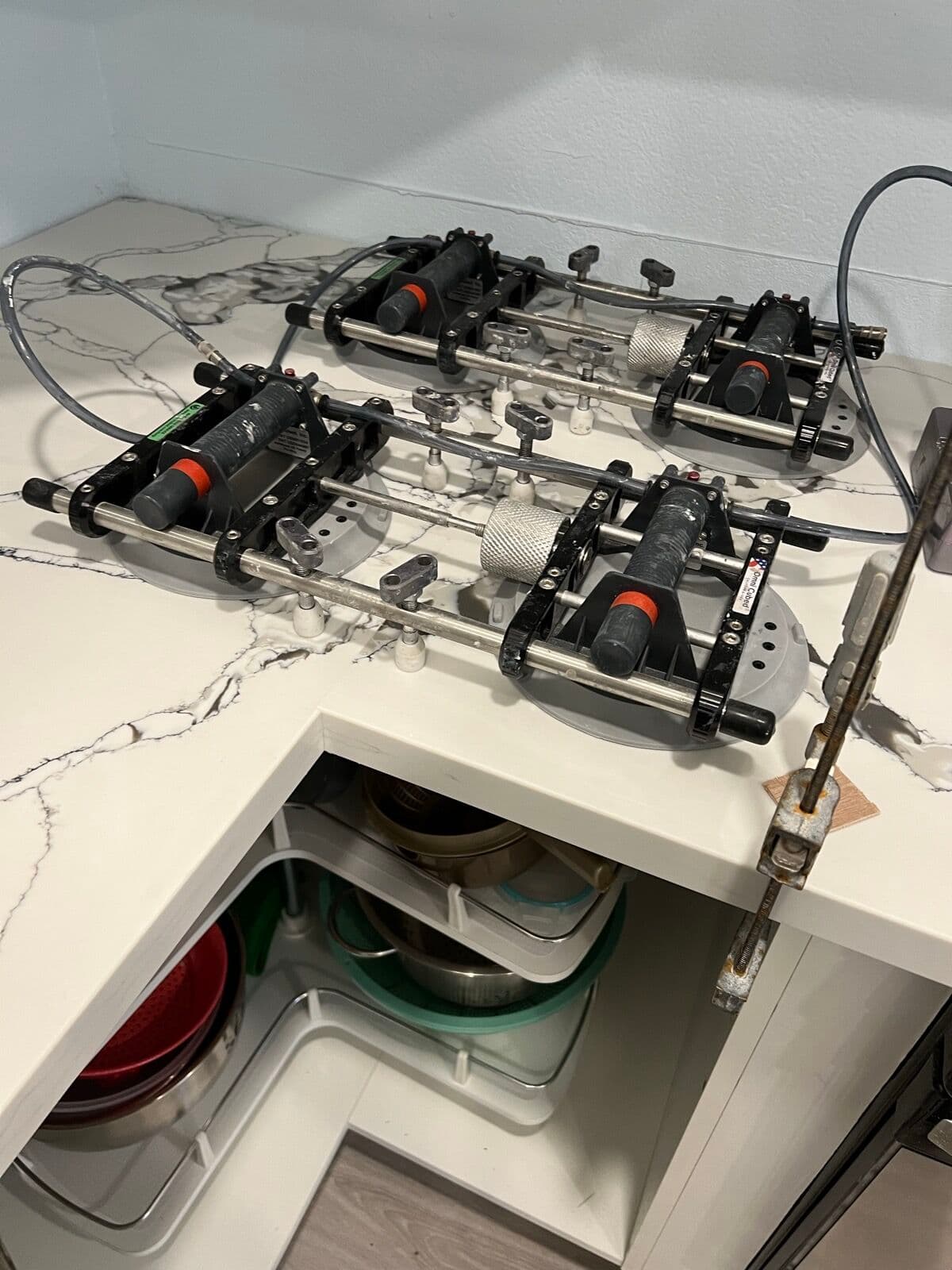 Vacuum seam-setting clamps positioned on a marble-veined countertop joint during installation