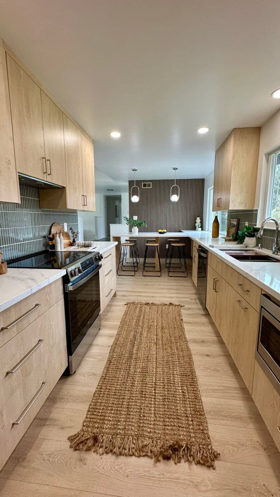 Galley view of the kitchen with range, jute runner, and bar seating by the slat wall in the background