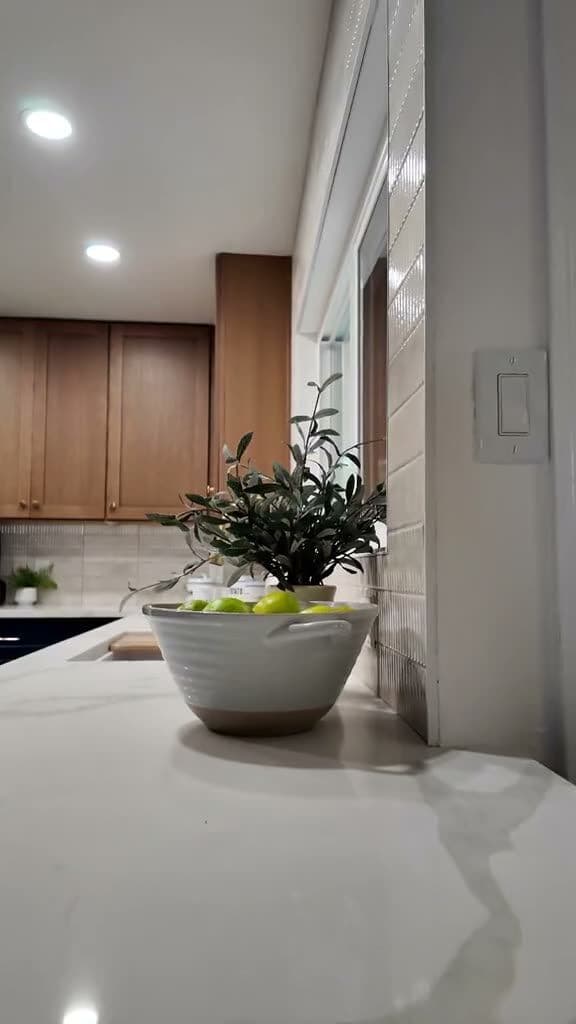 Styled quartz-look countertop with a bowl of limes and a potted plant beside the tiled wall