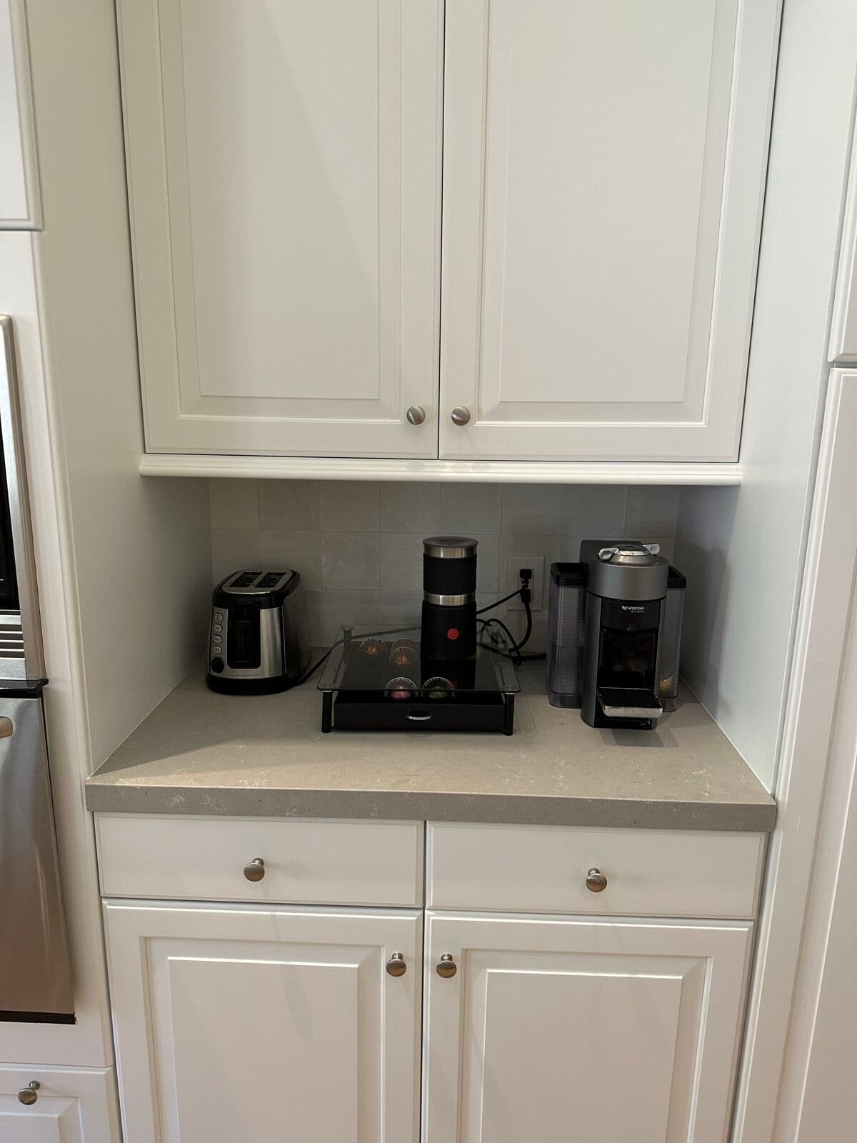 Coffee-station nook with quartz counter and square-tile backsplash between white upper and lower cabinets