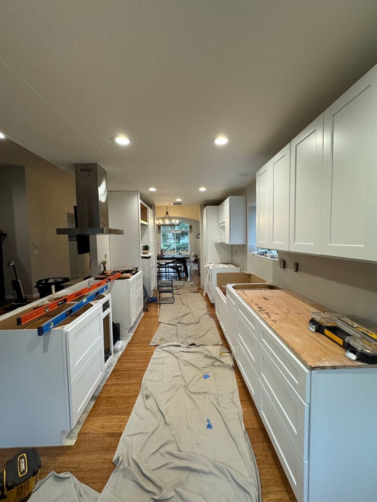 Base cabinets with shaker doors and drawer fronts installed, levels resting on the island cabinet frames