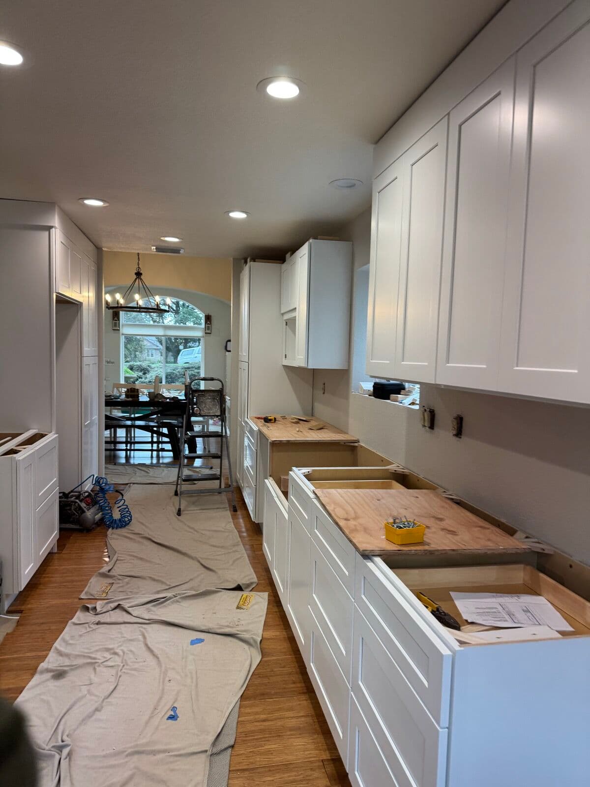 White shaker upper cabinets with crown molding above base cabinets topped with plywood templates