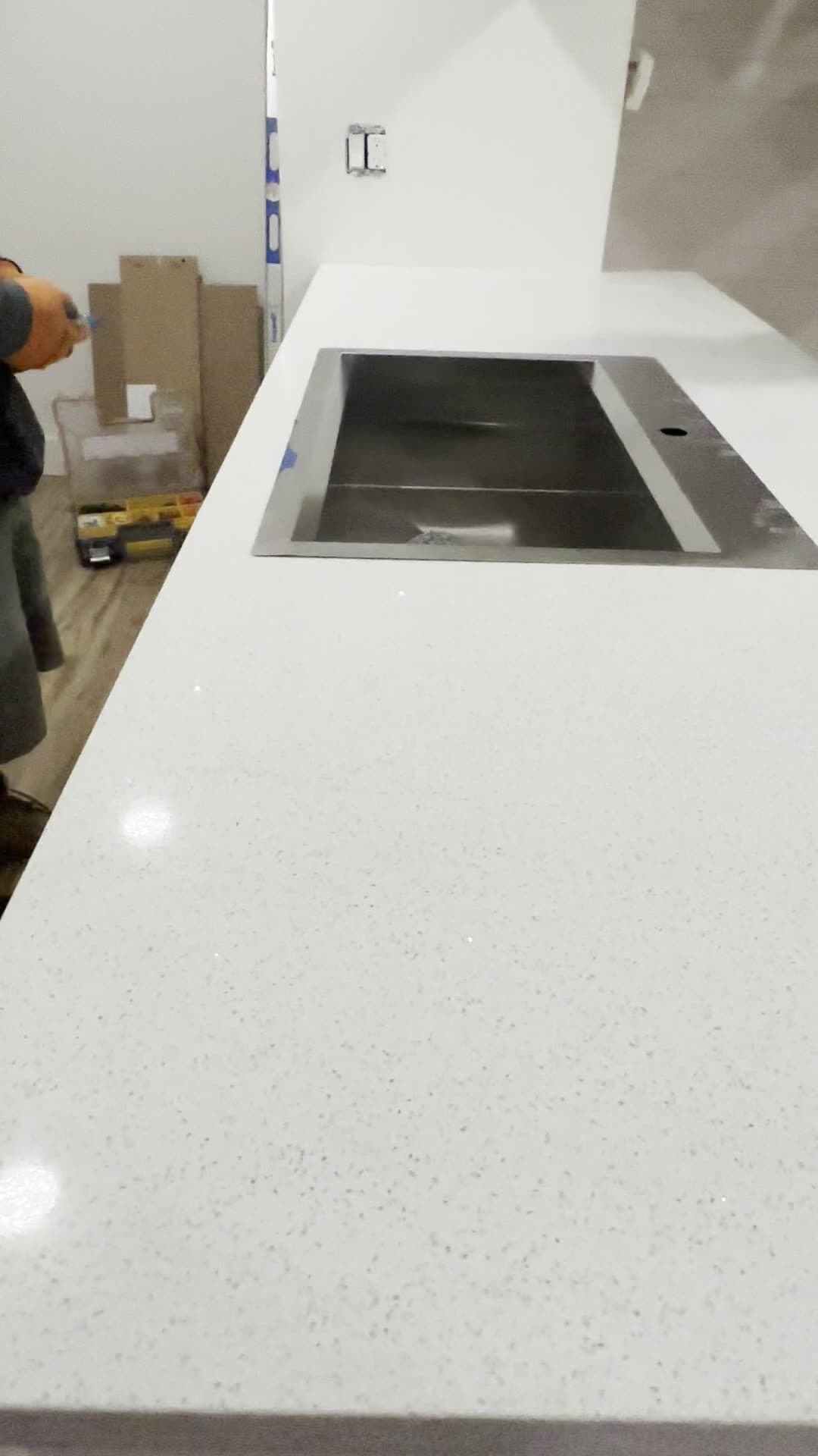 Black stainless single-basin sink set into a white sparkle quartz countertop