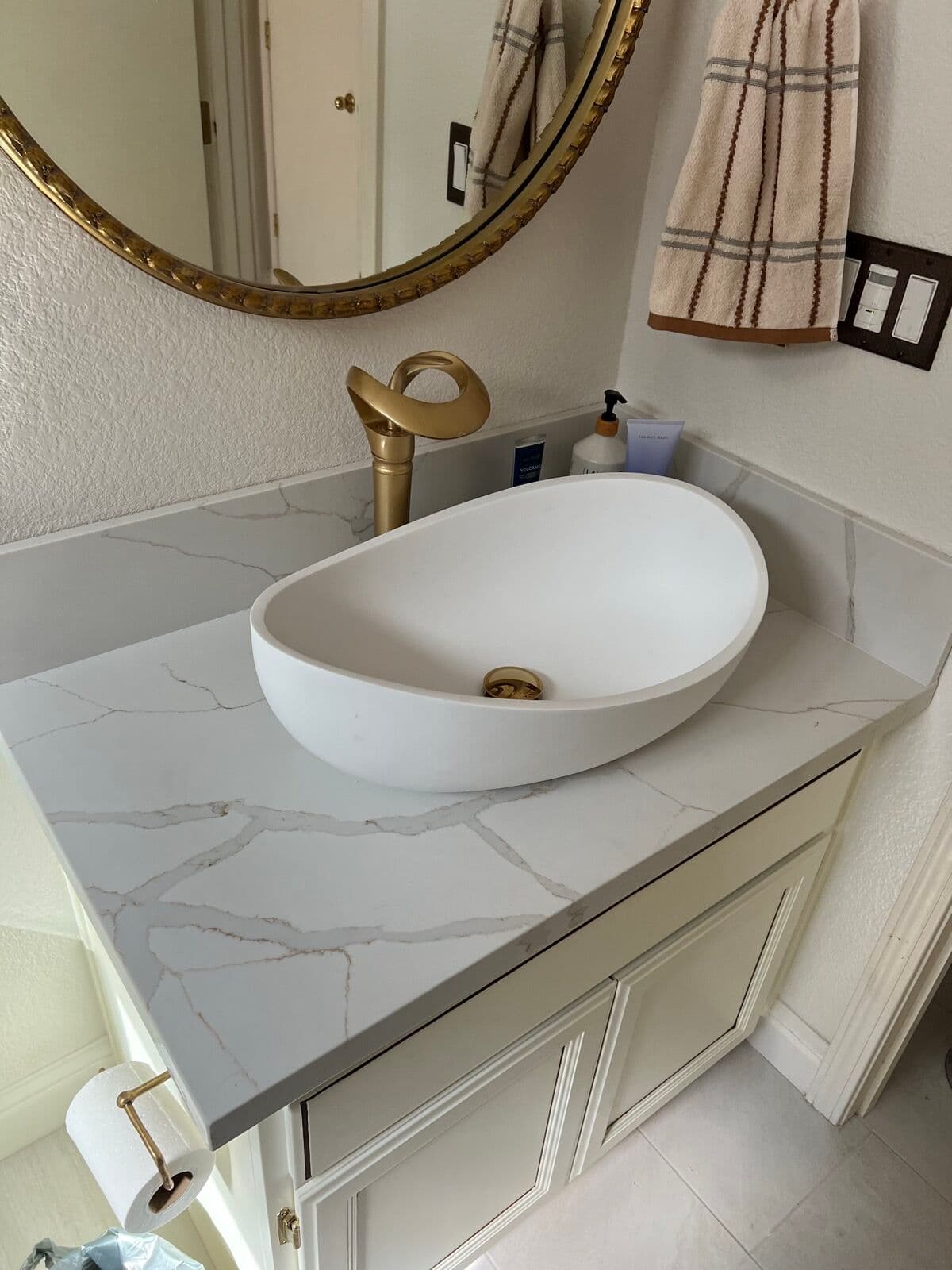 Vanity with quartz-look counter, vessel sink and brass waterfall faucet