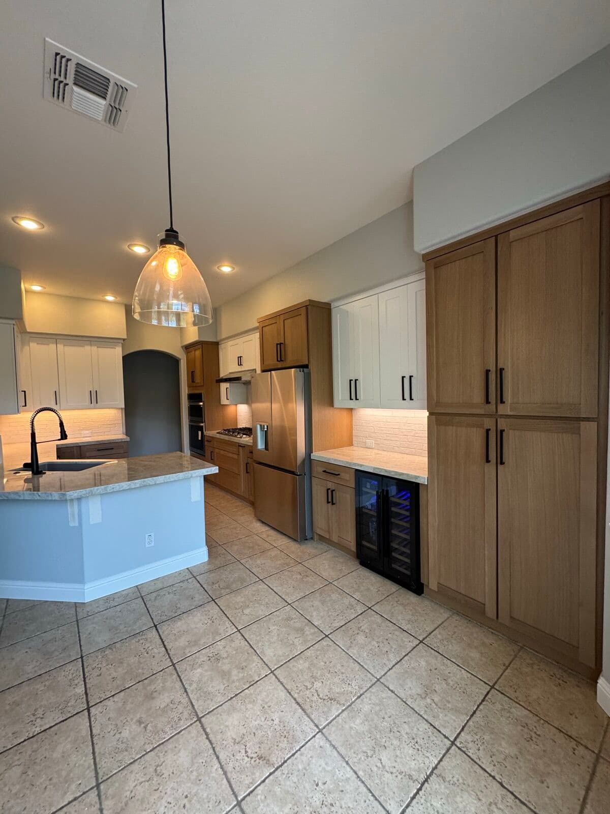 Floor-to-ceiling white-oak pantry cabinets beside a kitchen run