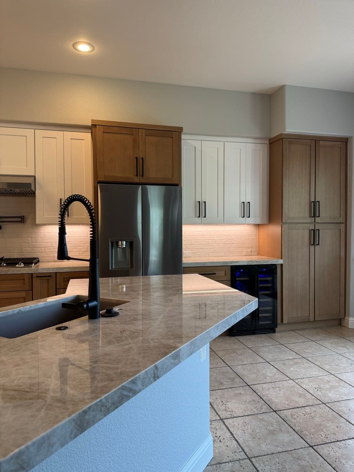 New stone countertop on the island with the kitchen appliance wall beyond