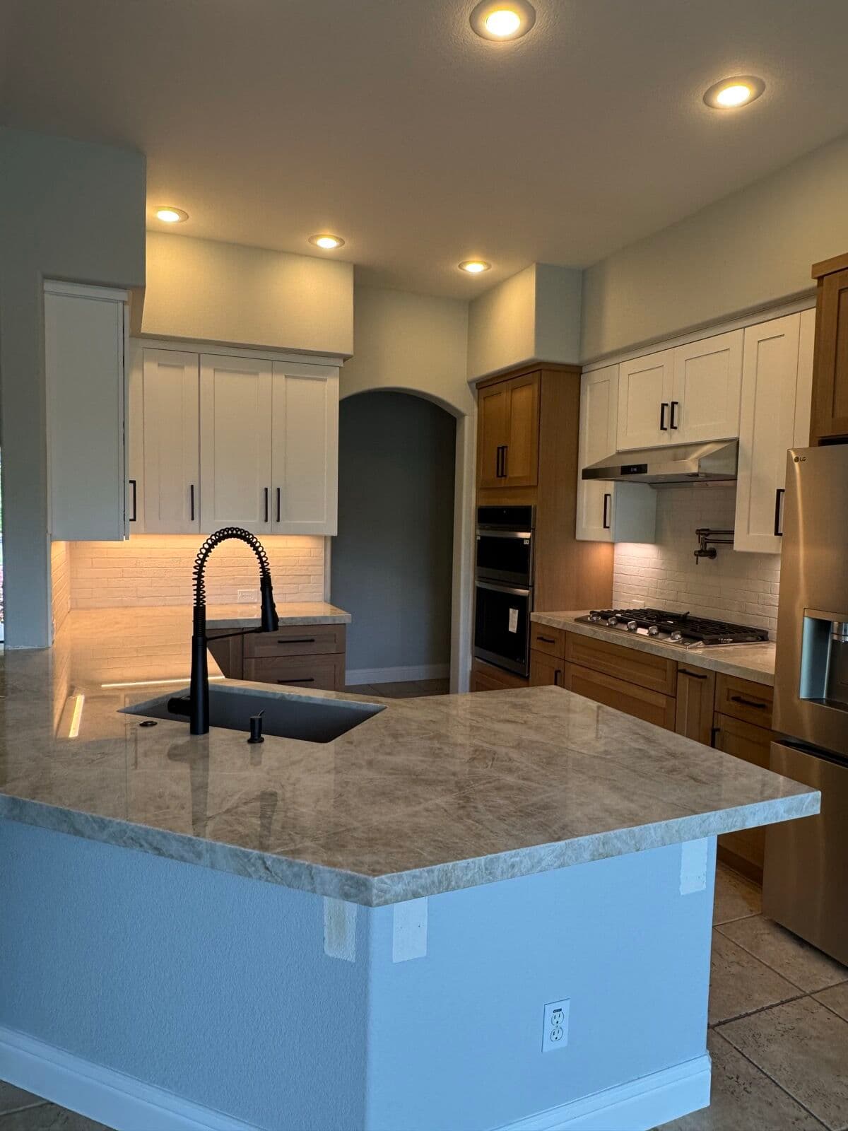 Angled peninsula with a thick stone countertop, black undermount sink and matte black faucet