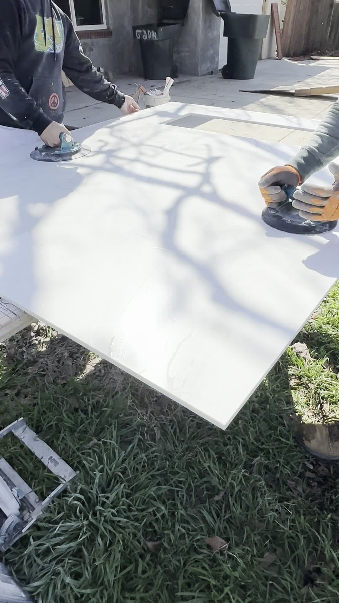 Two installers carrying an oversized stone panel with suction lifters