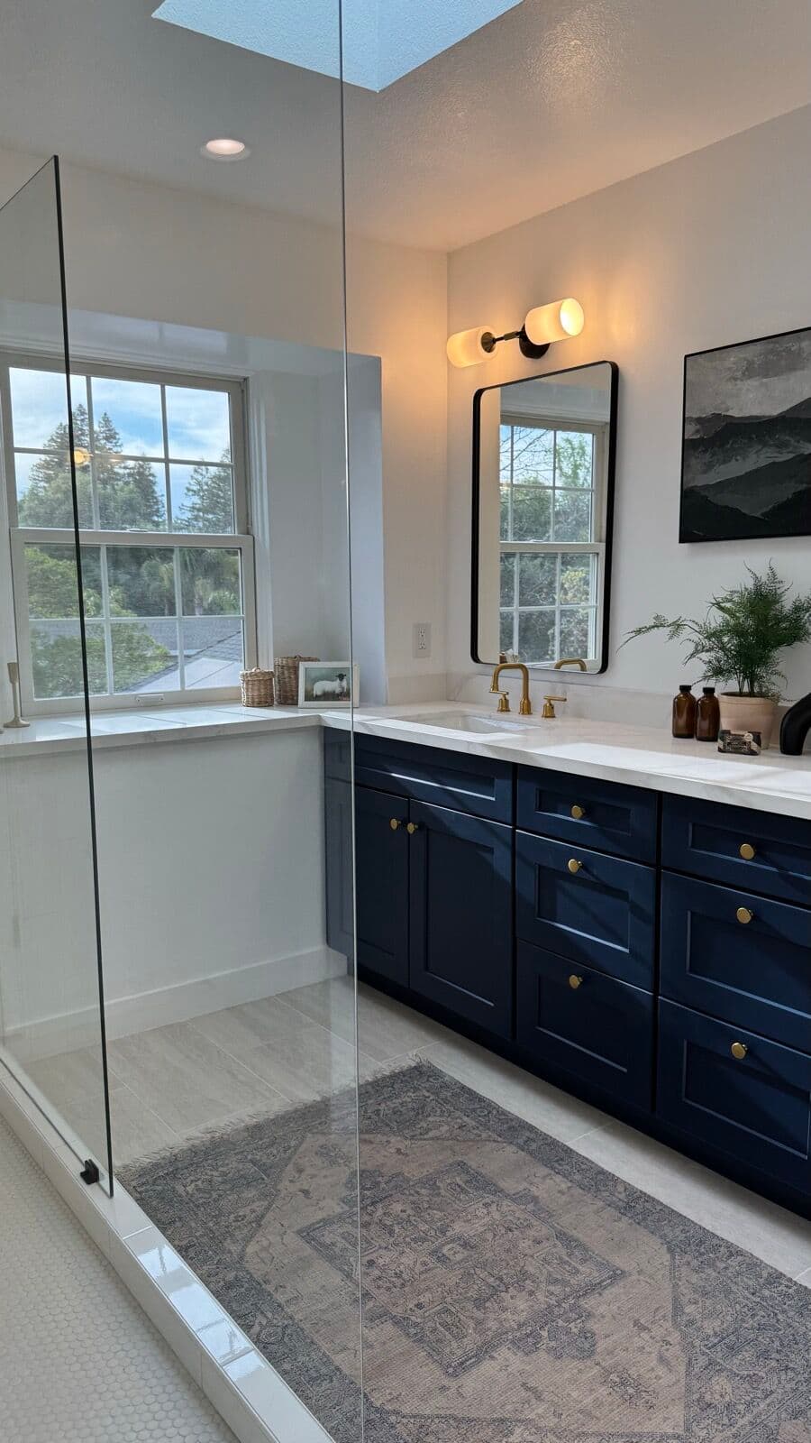 Bathroom with a low-threshold glass shower panel, skylight and navy vanity