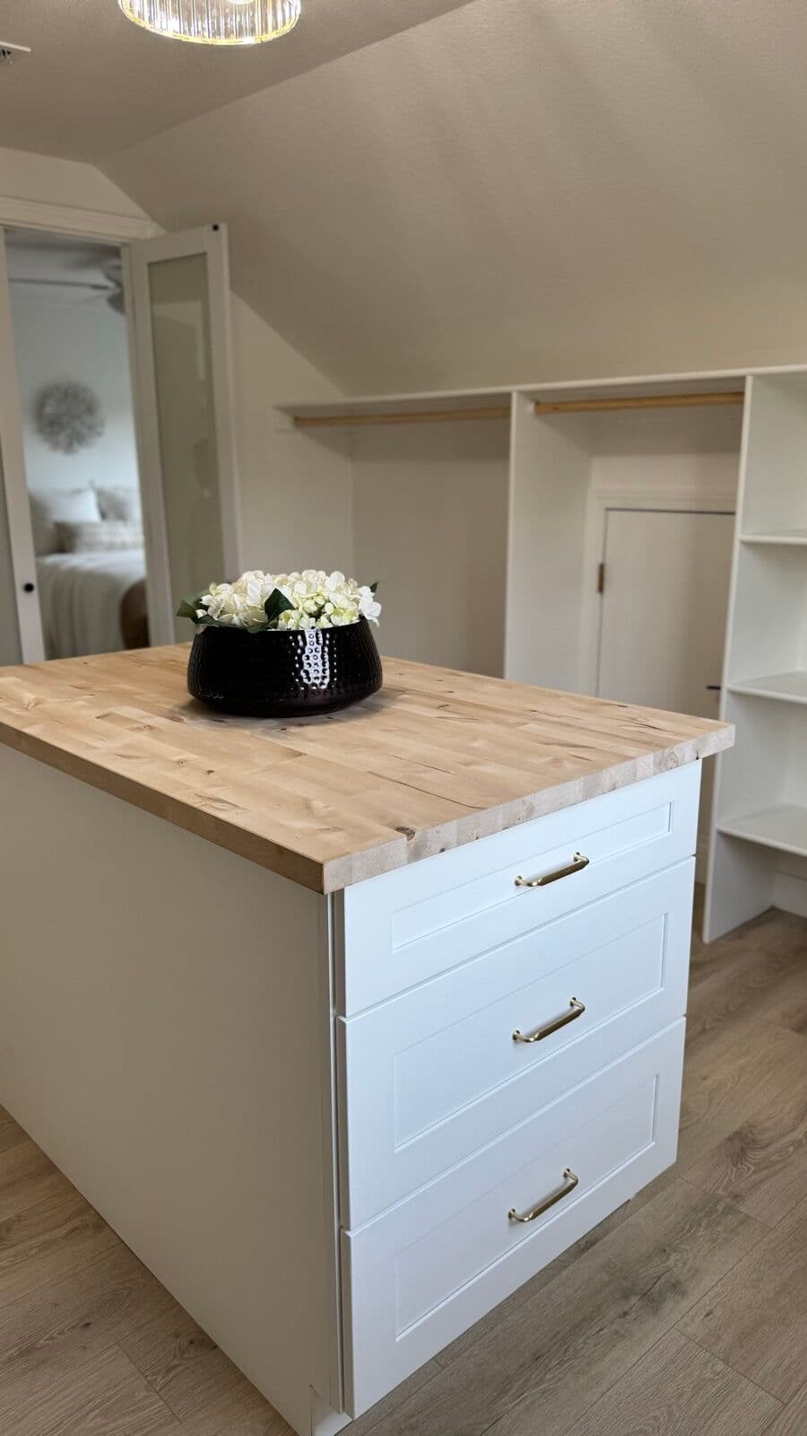 Walk-in closet island dresser with butcher-block top and built-in shelving