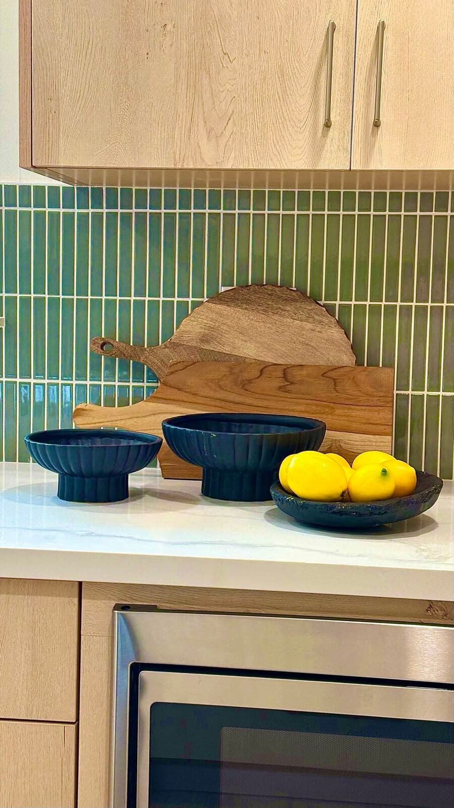 Sage-green stacked tile backsplash behind a quartz counter
