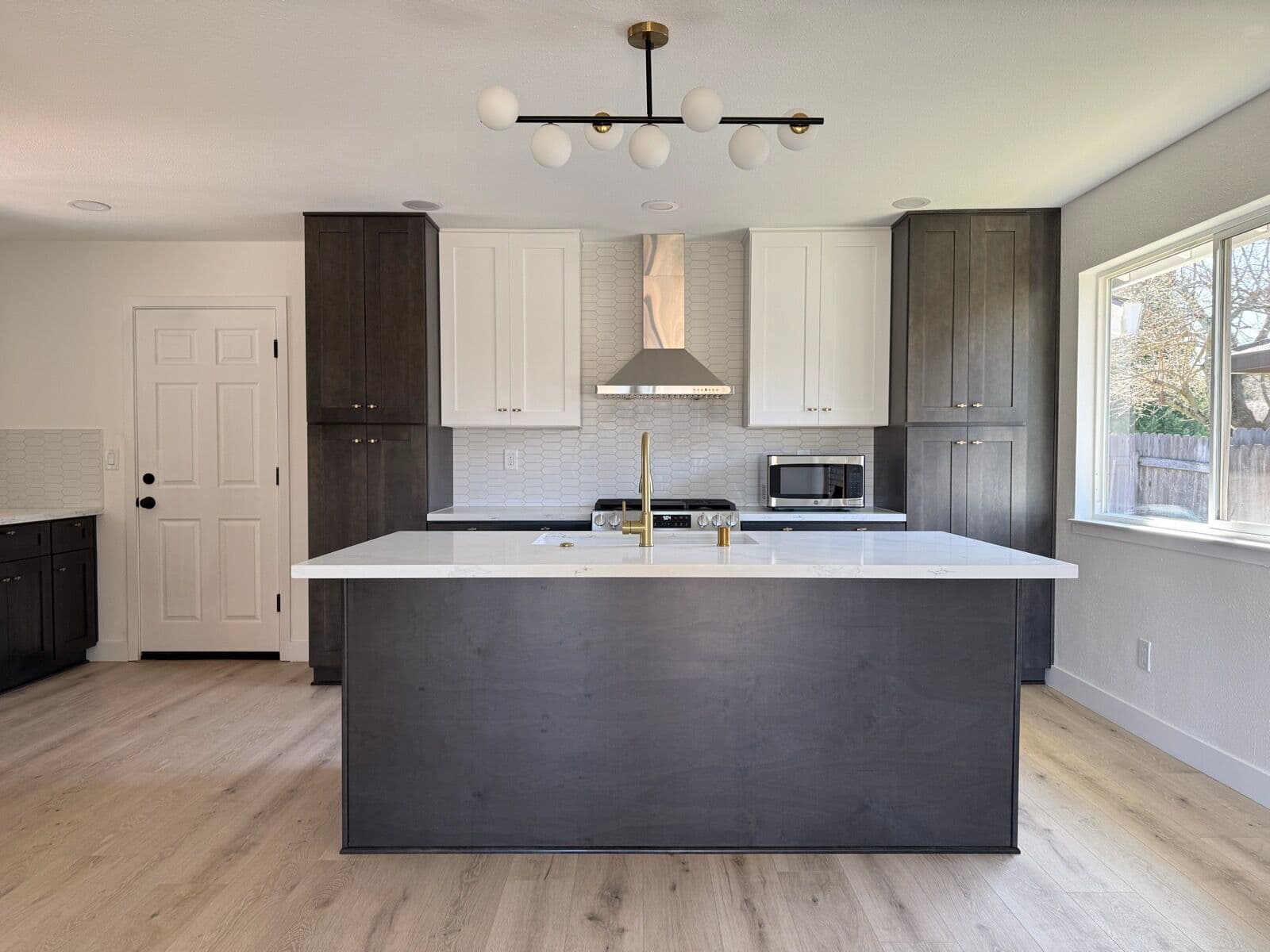 Kitchen island with charcoal base cabinets, white quartz top and brass faucet