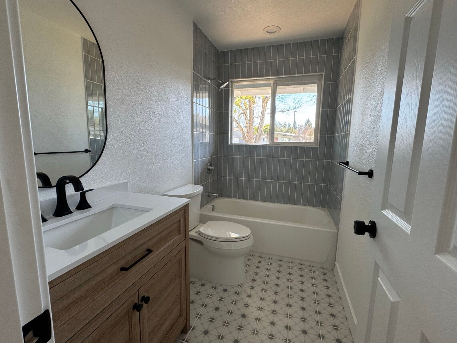 Bathroom with patterned tile floor, retiled tub surround and new vanity
