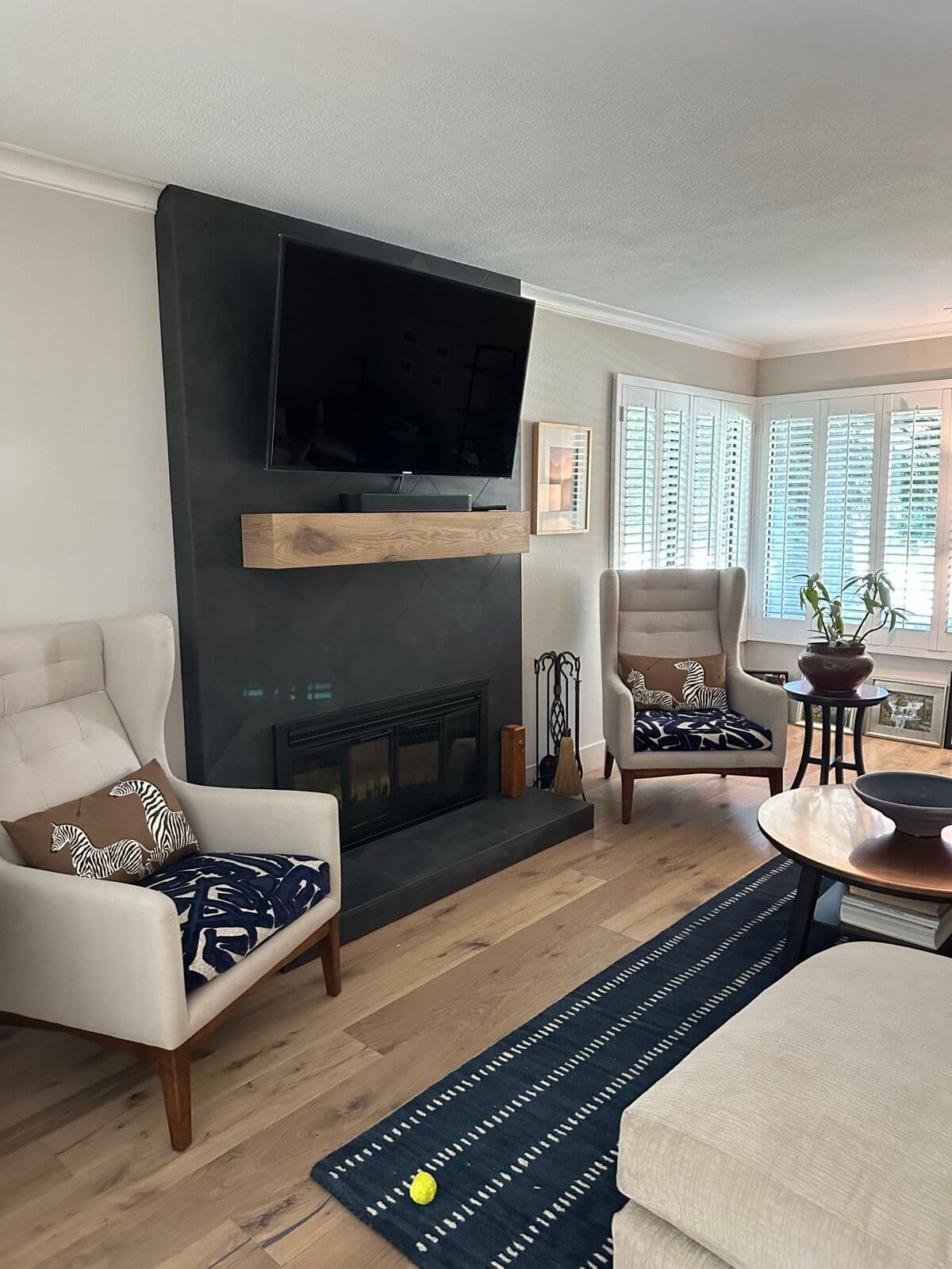 Television mounted over a resurfaced fireplace with a white-oak mantel