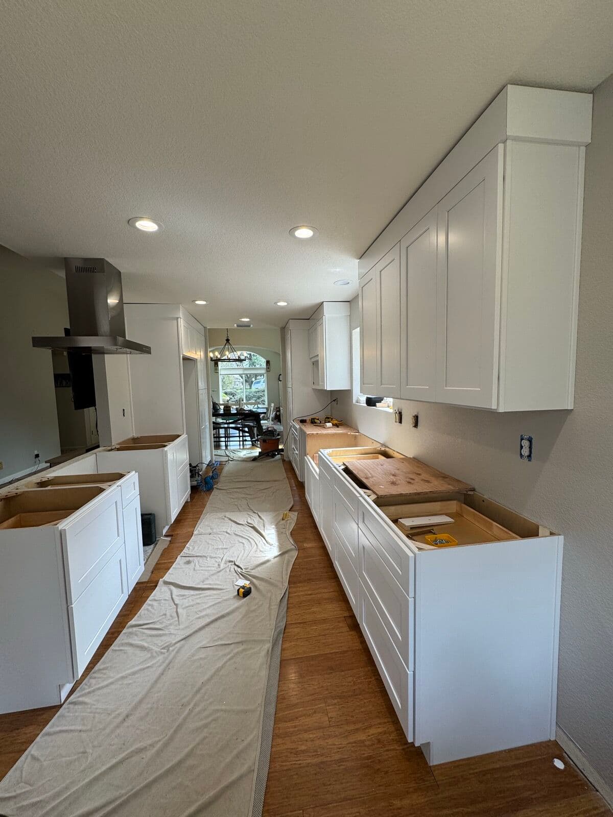 Galley kitchen with white shaker cabinets installed and plywood template tops on the base cabinets, ready for countertop templating