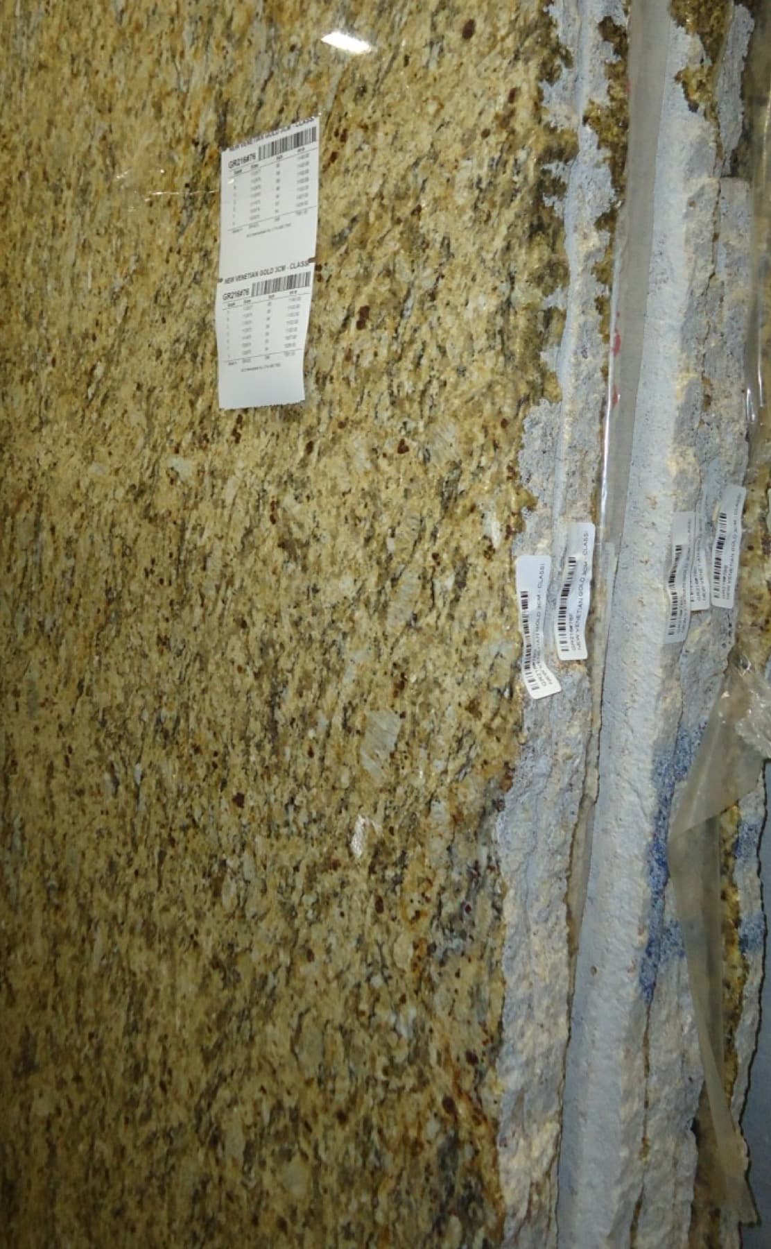 Granite slabs standing on edge in a supplier warehouse, each tagged with its bundle number